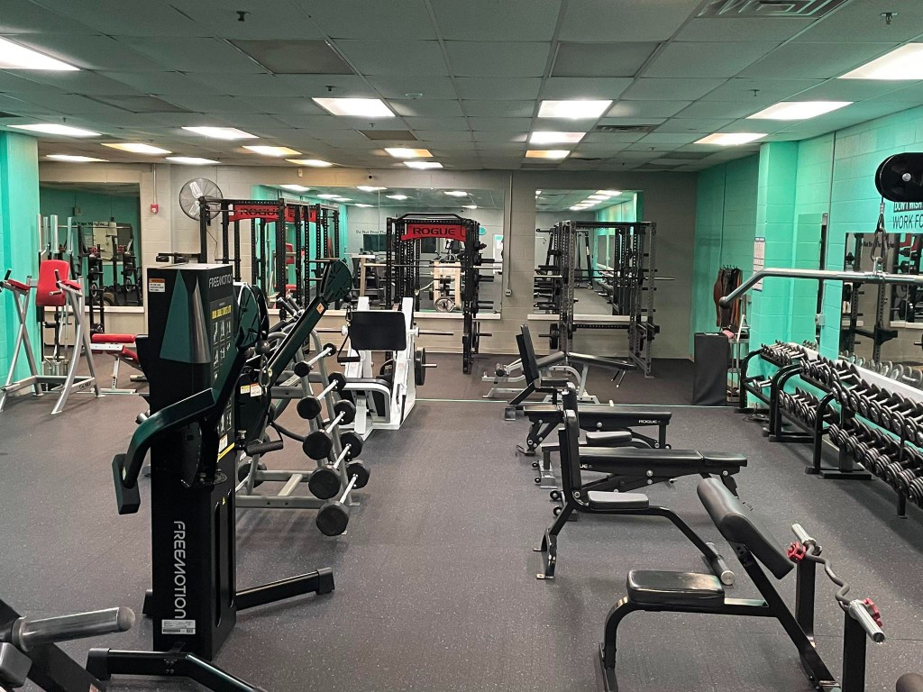 TBC Wellness Center weight room with free weights, cable machines, and power racks.